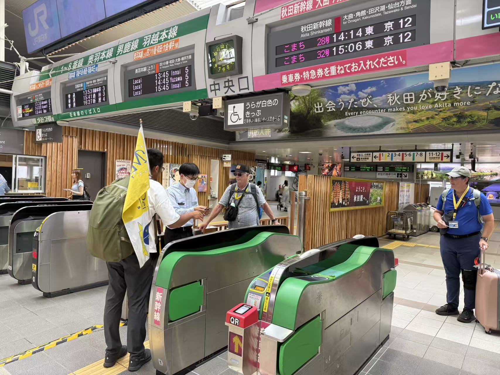 A guide assisting pilgrims at the ticket gates inside Akita Station