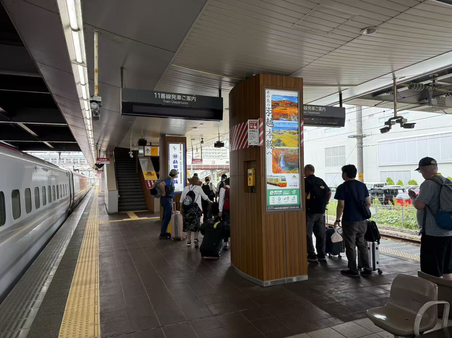 Pilgrims with luggage waiting beside a train at a station in Japan