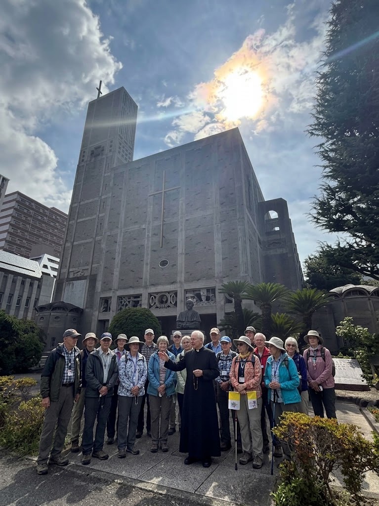 Pilgrimage group with a priest outside a Catholic church