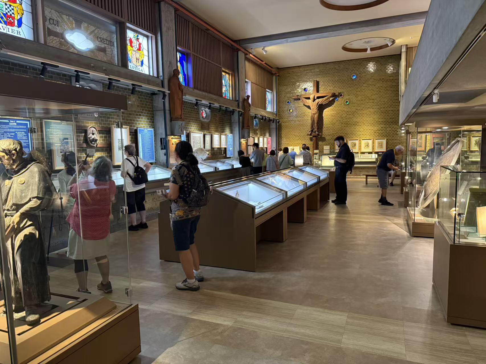 Pilgrims visiting a Catholic museum with historical exhibits and a large crucifix