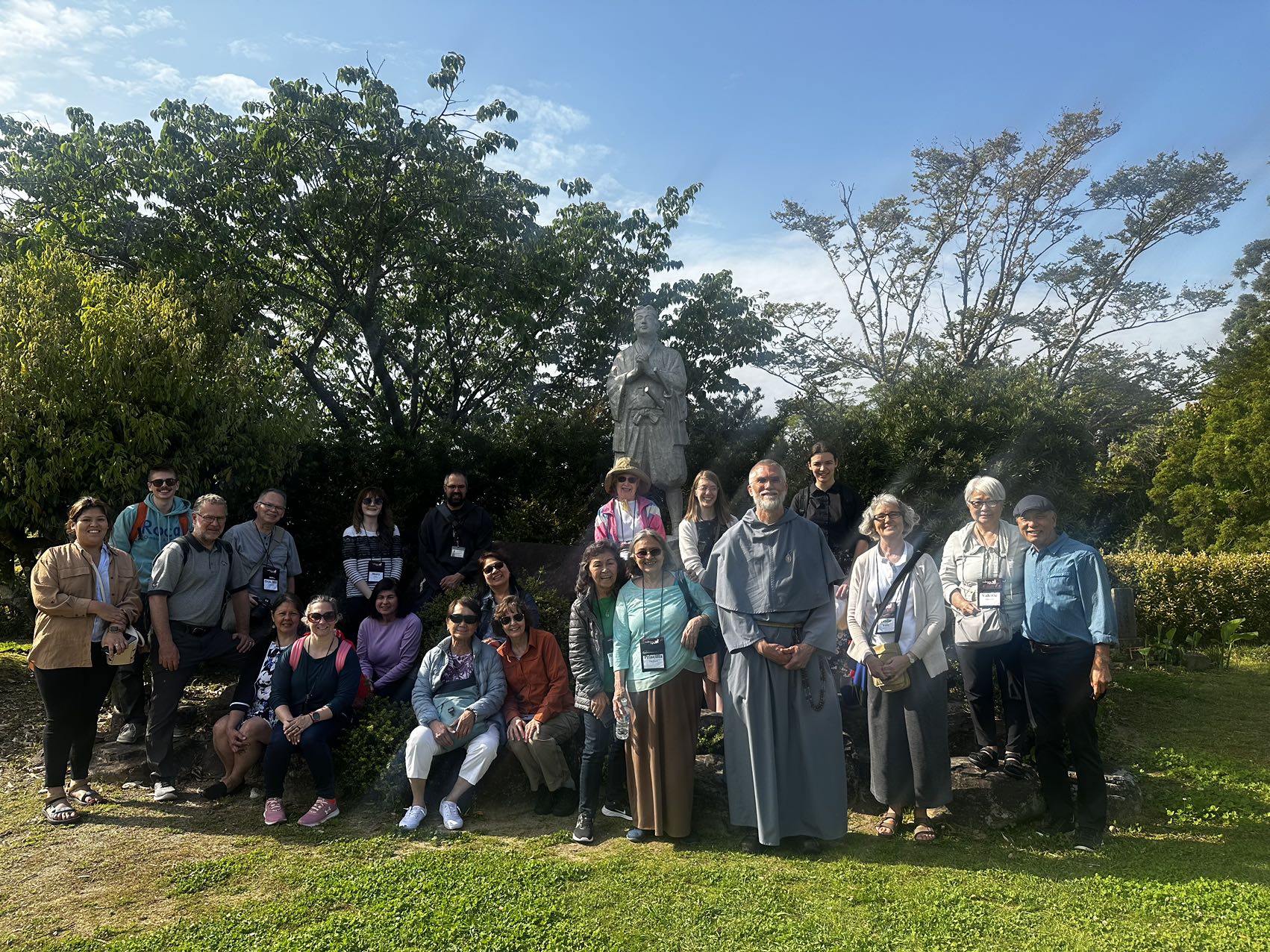 Catholic pilgrimage group gathered beside a memorial statue in Japan